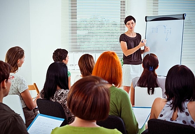 Frau vor einem Flipchart gibt Unterricht © Getty Images Signatures/izusek via Canva Pro